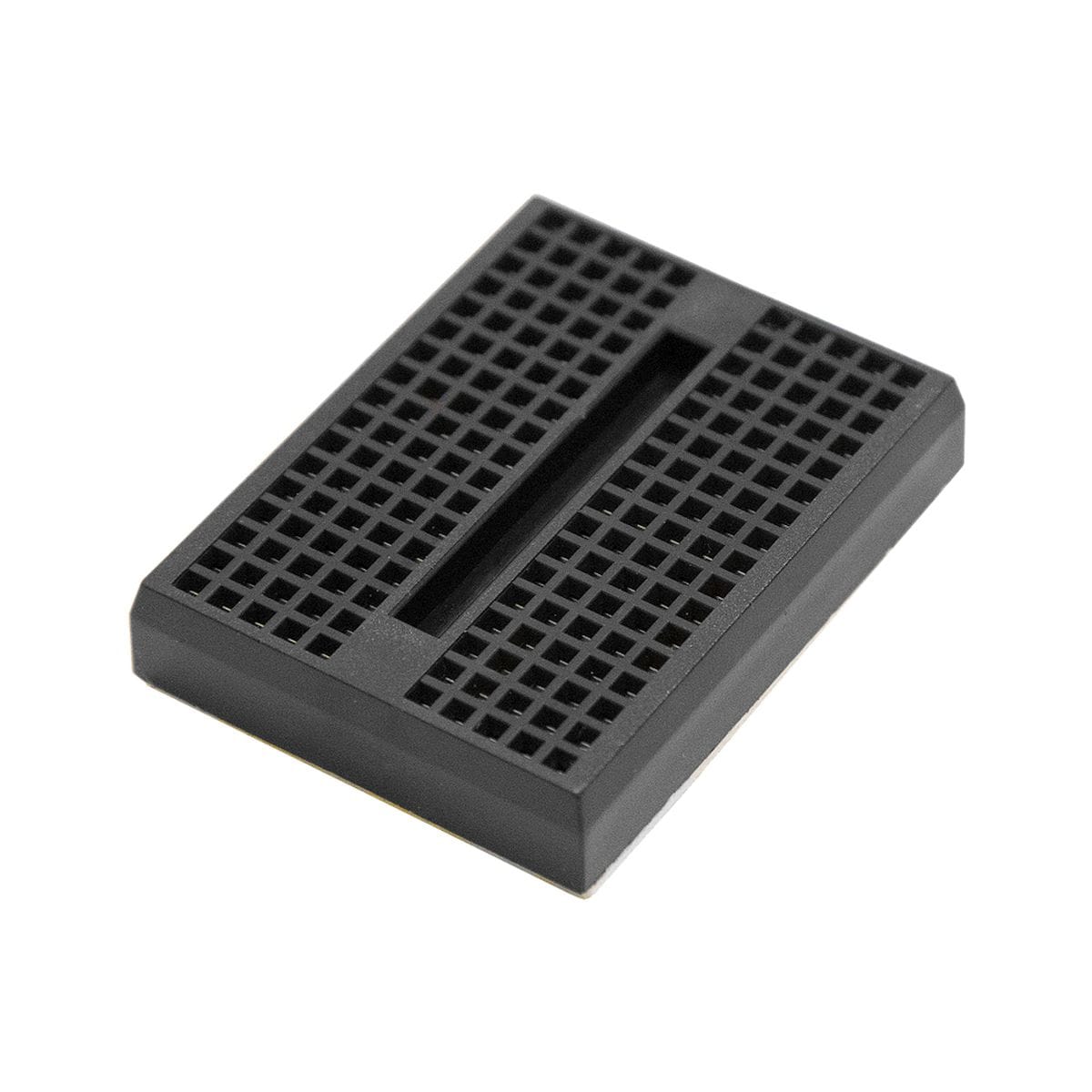 Sötétkék 170 lyukas mini breadboard előtérben, háttérben fehér és zöld próbapanelekkel, Arduino bekötés gyakorlásához.