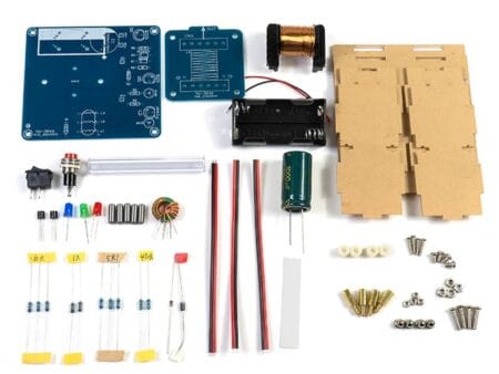 DIY elektromágneses ágyú készlet, magasfeszültségű tekercses gyorsítóval, nyomtatott áramköri lappal és forrasztásra váró alkatrészekkel, demonstrációs vagy oktatási célra.