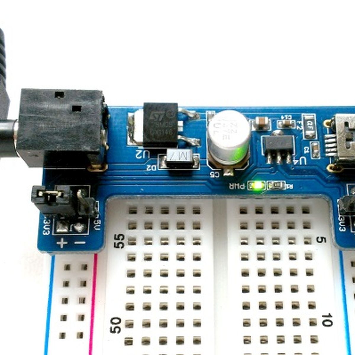 Kék breadboard tápmodul kapcsolókkal, USB bemenettel és DC tápcsatlakozóval, 3,3 V vagy 5 V próbapaneles tápellátáshoz.