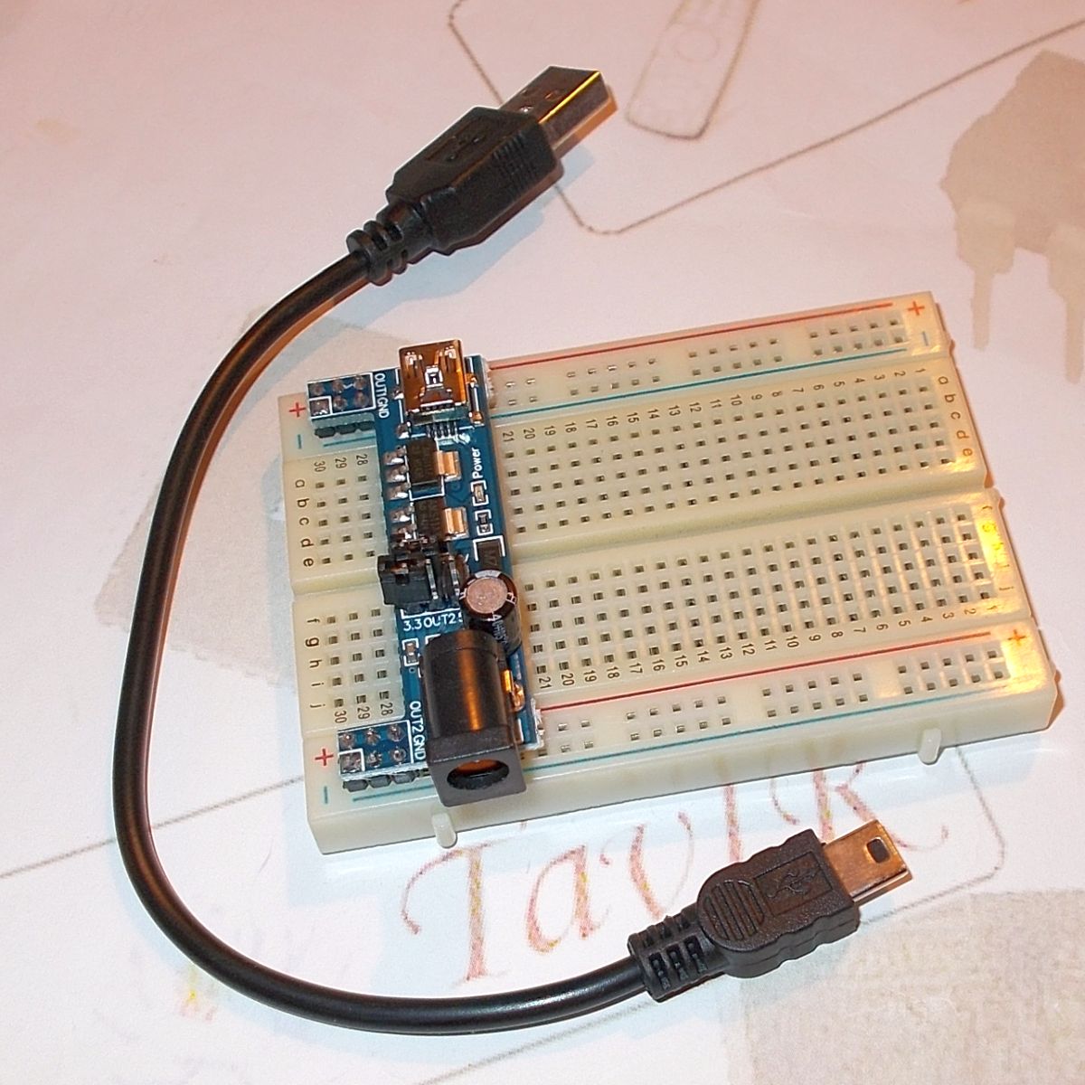 Kompakt tápegység modul próbapanelhez, kék NYÁK-lapon miniUSB csatlakozóval, DC aljzattal és kapcsolható kimenetekkel Arduino bekötésekhez.