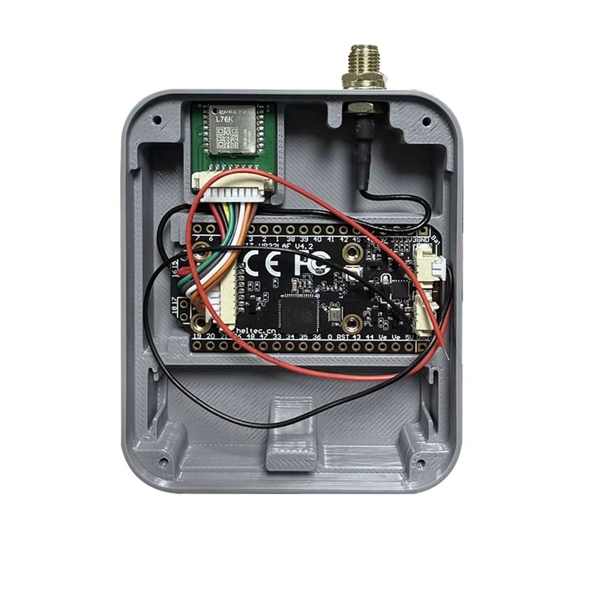 Szürke ház belseje felnyitva, benne Heltec fejlesztőpanel, vezetékek, GPS modul és antenna kábel; LoRa projekt ház belső elrendezése 14500 akkumulátoros kialakításhoz.