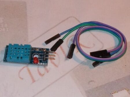 Egy DHT11 digitális hőmérséklet- és páratartalom-érzékelő modul közelről, háromlábú csatlakozóval, mikrokontrolleres projektekhez, Arduino-kompatibilitással.